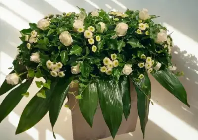 Grabgesteck mit weißen Rosen, kleinen weißen Blüten und dekorativem Grün