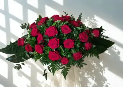Grabgesteck mit weißen Rosen, kleinen weißen Blüten und dekorativem Grün