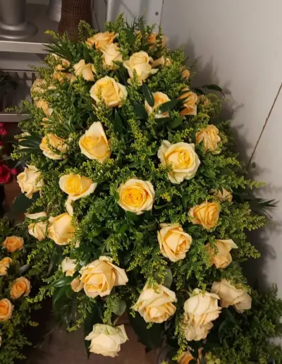 Trauergesteck mit cremefarbenen Rosen und dichtem grünem Beiwerk