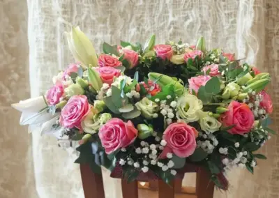 Trauergesteck mit rosa Rosen, weißen Lilien, Schleierkraut und Eukalyptus.