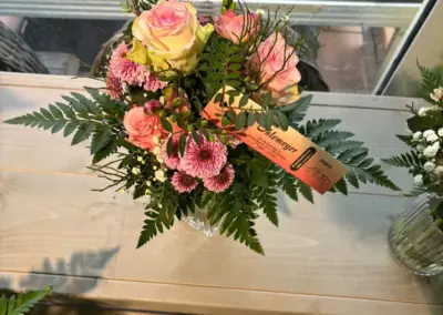 Florales Gesteck mit rosa Rosen, Chrysanthemen und dekorativem Grün