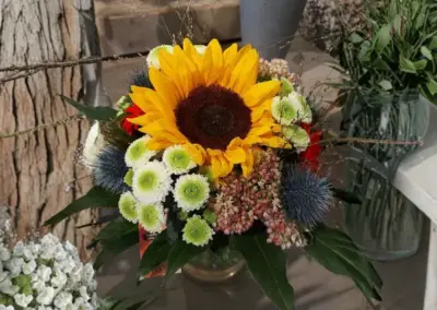 Blumenstrauß mit großer Sonnenblume, weißen Blüten und blauen Disteln