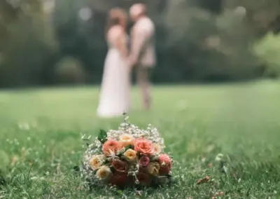 Brautstrauß mit Rosen in Apricot und Creme und Schleierkraut auf einer Wiese bei einer Hochzeit