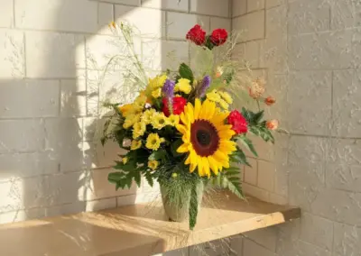 Farbenfroßer Blumenstrauß mit Sonnenblume, roten Nelken und gelben Blüten