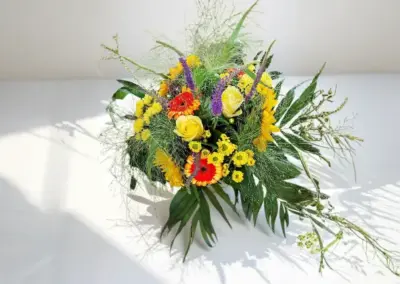 Farbenfroßer Blumenstrauß mit Sonnenblume, roten Rosen, gelben Blüten und violetten Akzenten
