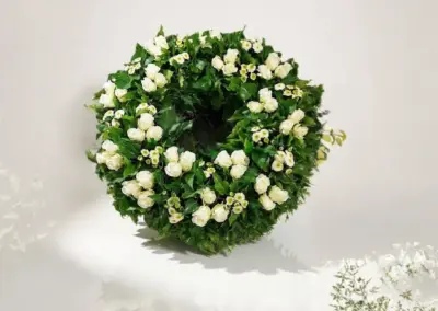 Grüner Trauerkranz mit weißen Rosen und kleinen weißen Blüten
