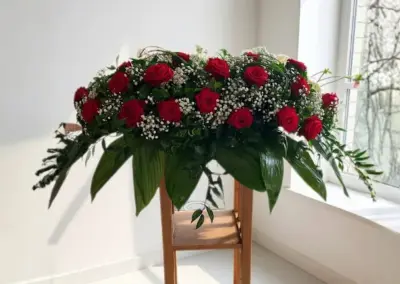 Sargschmuck mit roten Rosen, Schleierkraut und üppigem grünen Beiwerk