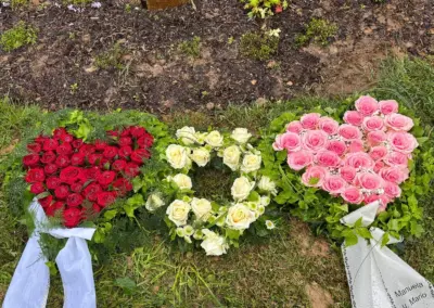 Trauergestecke in Herzform aus roten, weißen und rosa Rosen